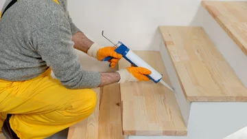 Handwerker renoviert Holztreppe, Montage neuer Holzsstufen